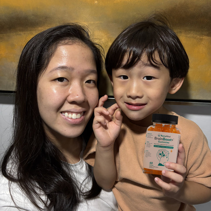 A mother and her young son smiling, the boy holding up a bottle of BrainBoost+ gummies