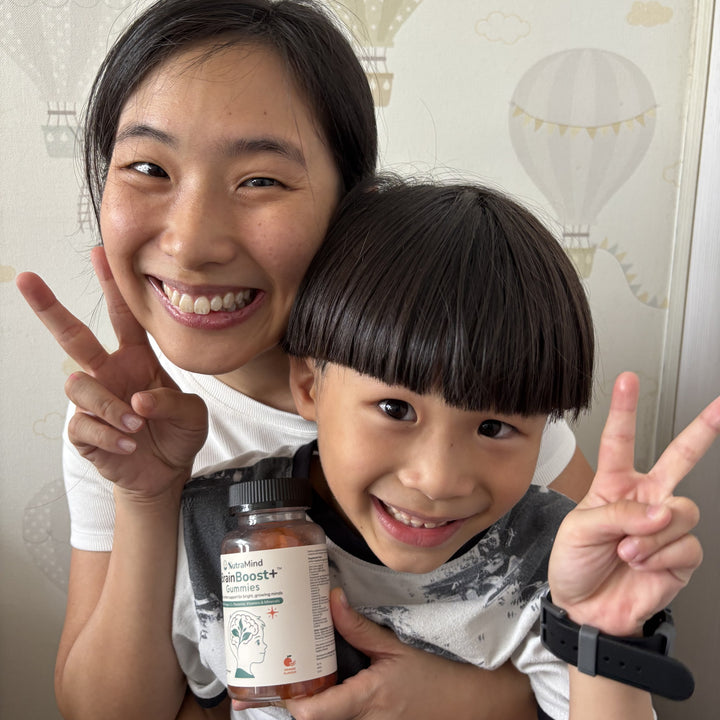 A mother and her young daughter smiling together, holding a bottle of BrainBoost+ gummies