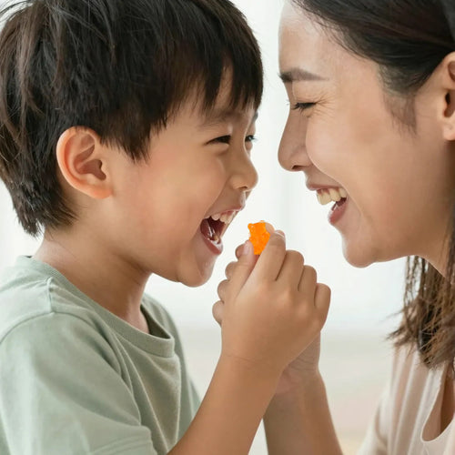 A mother and her young son laughing together as he holds up a BrainBoost+ gummy